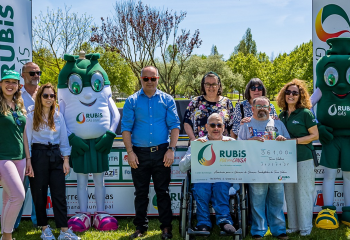 Entrega do cheque simbólico da iniciativa Rubis por uma Causa à APECI, com representantes da instituição e as mascotes da Rubis Gás num espaço ao ar livre.