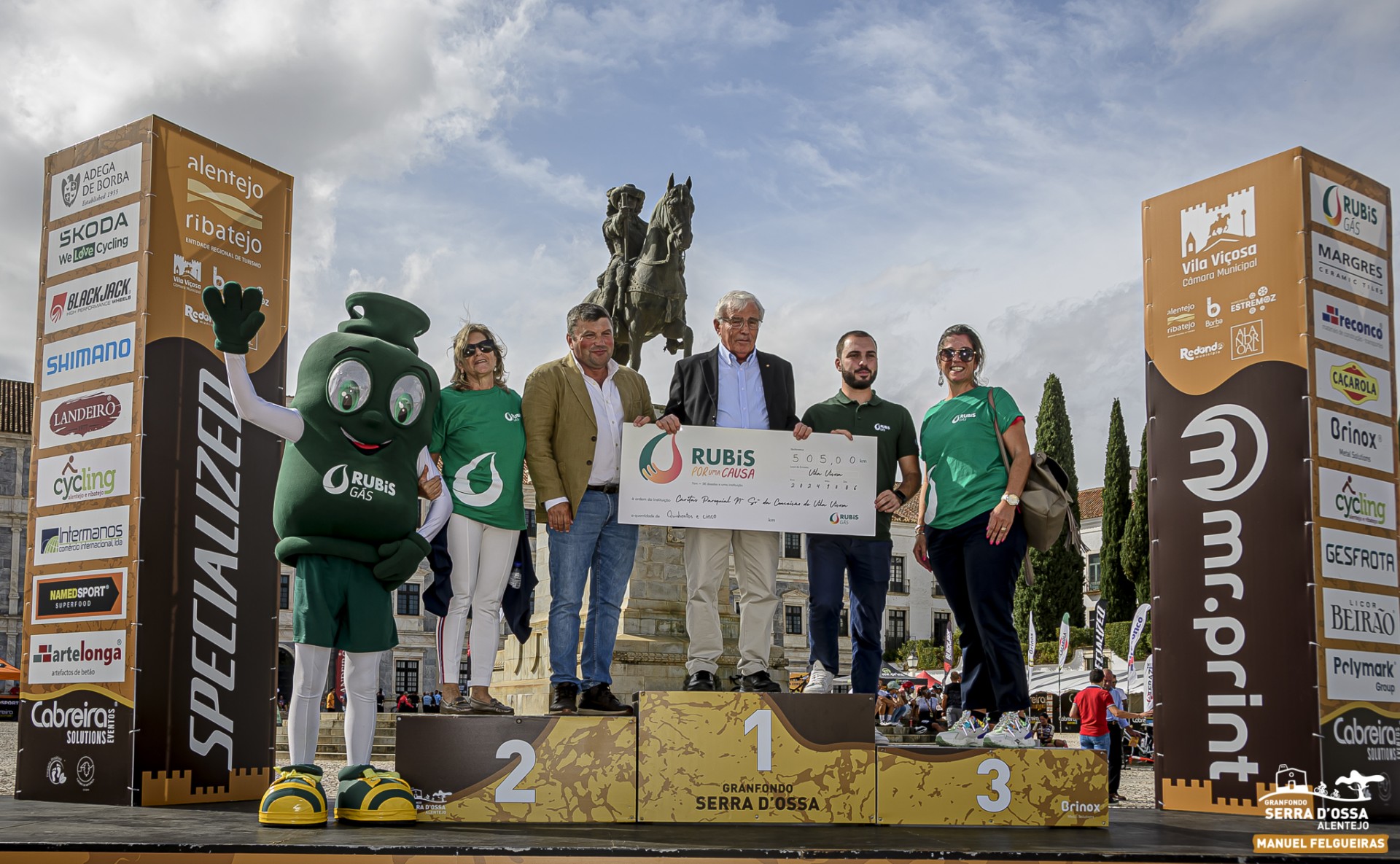 Entrega do cheque simbólico da iniciativa Rubis por uma Causa à Cáritas Paroquial no pódio do Granfondo Serra D'Ossa, com a mascote da Rubis Gás.