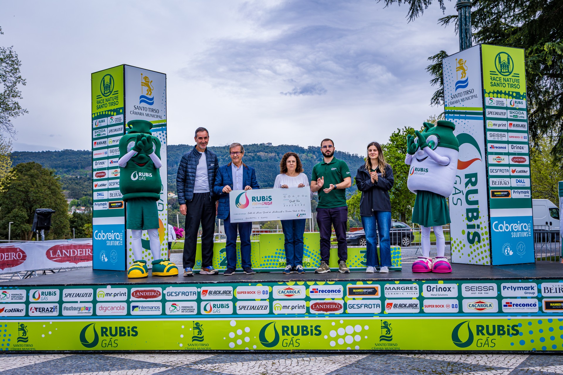 Entrega do cheque simbólico da iniciativa Rubis por uma Causa ao CASATIR, com representantes e as mascotes da Rubis Gás no pódio em Santo Tirso.